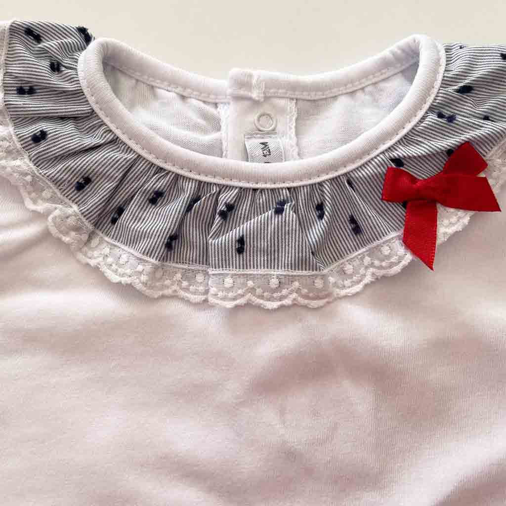 Detalle volante en camiseta de conjunto para bebé niña de dos piezas. Primavera-Verano. Marca Calamaro. Color , azul y blanco con lazo.